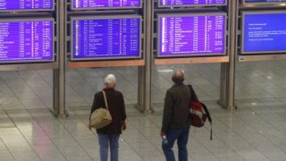 Passengers look at flight information displays during a strike at Frankfurt airport