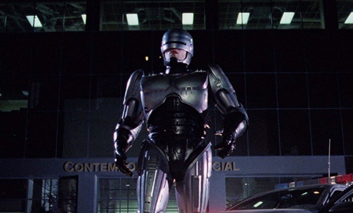 4. "Робокоп" (RoboCop, 1987)

Бъдещето не е особено приятно - консумеризмът е завладял обществото, престъпността вирее навсякъде, а властта е в ръцете на огромни корпорации. Алекс Мърфи (Питър Уелър) е полицай, който става жертва на жестоко (ама наистина ужасяващо) убийство. Мърфи възкръсва за нов живот, след като останките му са използвани за проекта "Робокоп" - създаването на комбинация между човек и машина, която по-ефективно да брани обществото. Но в този свят е трудно да определиш кои точно са "лошите".
Този киберпънк екшън е актуален и до днес, въпреки че е на повече от 30 години. Засяга теми като корупцията, авторитарната власт, влиянието на медиите, алчността и още. Има някаква ирония в частта за "алчността", защото филмът дава началото на цял франчайз от продължения, един римейк (задава се втори), анимационни и телевизионни сериали.
Верховен обаче няма общо с тях. Самият той първоначално е отвратен от сценария на филма, но с помощта на жена си вижда отвъд повърхността и възможността да се сатиризира американското общество (и сякаш неизбежното бъдеще, което вече може би е настояще).