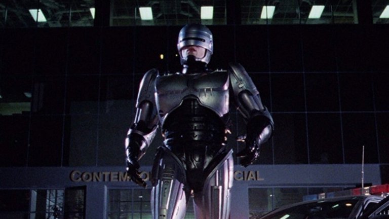 4. "Робокоп" (RoboCop, 1987)

Бъдещето не е особено приятно - консумеризмът е завладял обществото, престъпността вирее навсякъде, а властта е в ръцете на огромни корпорации. Алекс Мърфи (Питър Уелър) е полицай, който става жертва на жестоко (ама наистина ужасяващо) убийство. Мърфи възкръсва за нов живот, след като останките му са използвани за проекта "Робокоп" - създаването на комбинация между човек и машина, която по-ефективно да брани обществото. Но в този свят е трудно да определиш кои точно са "лошите".
Този киберпънк екшън е актуален и до днес, въпреки че е на повече от 30 години. Засяга теми като корупцията, авторитарната власт, влиянието на медиите, алчността и още. Има някаква ирония в частта за "алчността", защото филмът дава началото на цял франчайз от продължения, един римейк (задава се втори), анимационни и телевизионни сериали.
Верховен обаче няма общо с тях. Самият той първоначално е отвратен от сценария на филма, но с помощта на жена си вижда отвъд повърхността и възможността да се сатиризира американското общество (и сякаш неизбежното бъдеще, което вече може би е настояще).