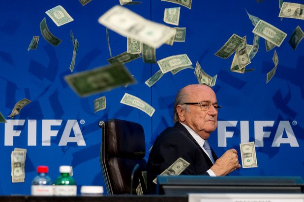 Блатер сред летящи банкноти... каква символика. Британски комик направи номера на пресконференция на уличения в корупция шеф на ФИФА.