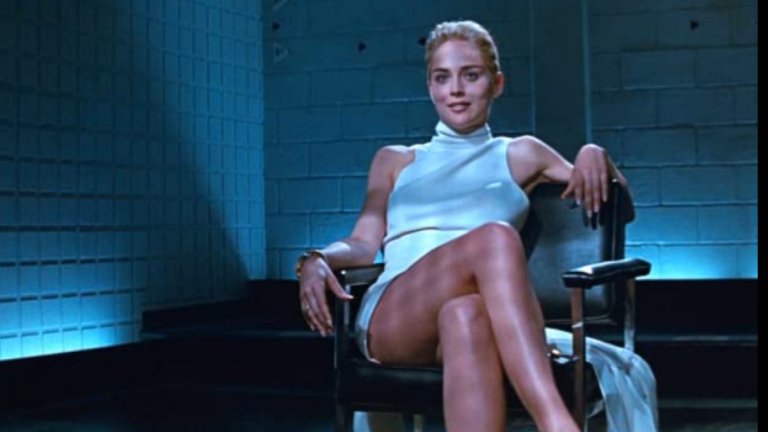 “Първичен инстинкт”
Няма как да минем и без най-емблематичната сцена, която върви ръка за ръка с бутона “Пауза”. Естествено, става въпрос за Шарън Стоун и онова иконично премятане на краката по време на полицейския разпит в “Първичен инстинкт”.
Персонажът на Стоун - Катрин Трамел, стои срещу група полицаи, разпитващия я за смъртта на партньора ѝ, а на един от въпросите тя разтваря крака и ги кръстосва. По отворените усти и избиващата пот на мъжете се предполага, че Трамел е без бельо, което е стимулирало зрителите да спират сцената, за да проверят дали и актрисата също не носи нищо под роклята.