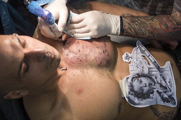 Художник татуира гърдите на млад мъж по време на 22-рия Международна конгрес на татусите във Франкфурт на Майн, Германия