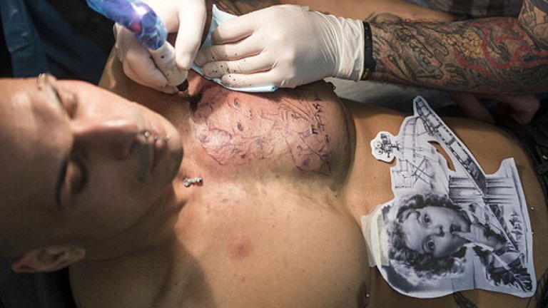 Художник татуира гърдите на млад мъж по време на 22-рия Международна конгрес на татусите във Франкфурт на Майн, Германия