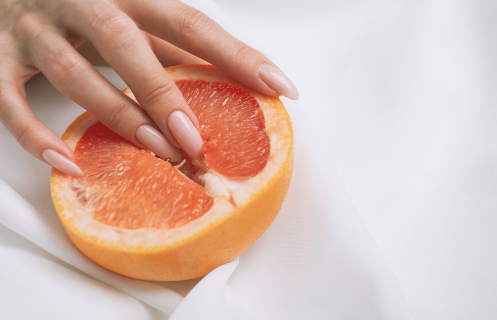 fingers in grapefruit on pink background. Sex and masturbation concept. sexy fruit composition. Vagina symbol.