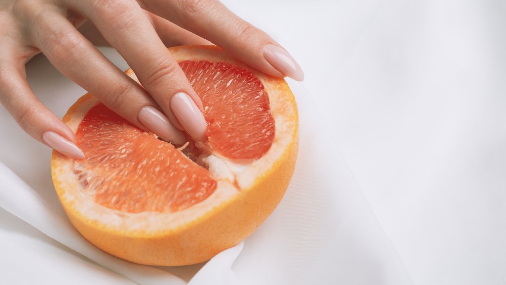 fingers in grapefruit on pink background. Sex and masturbation concept. sexy fruit composition. Vagina symbol.