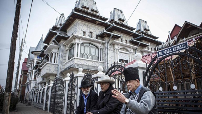 Костица стои пред къщата си на раздумка със съседите.