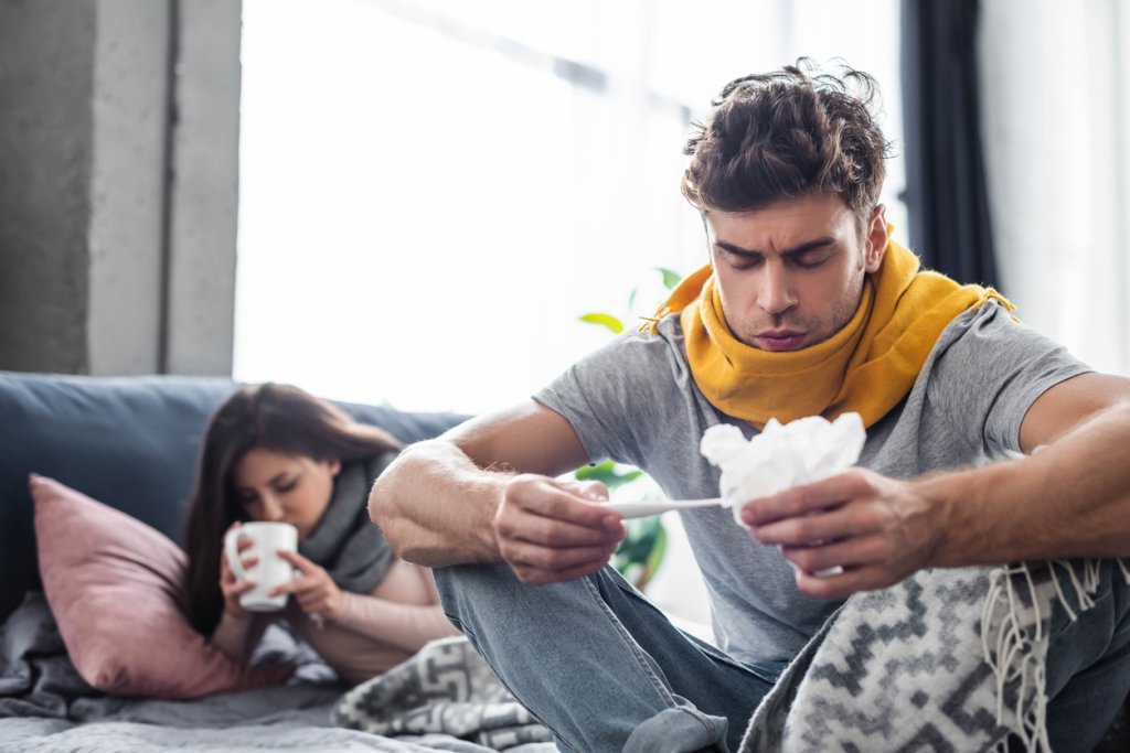 selective focus of sick boyfriend looking at thermometer and holding napkin