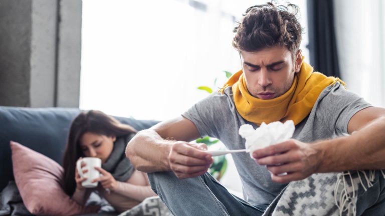 selective focus of sick boyfriend looking at thermometer and holding napkin
