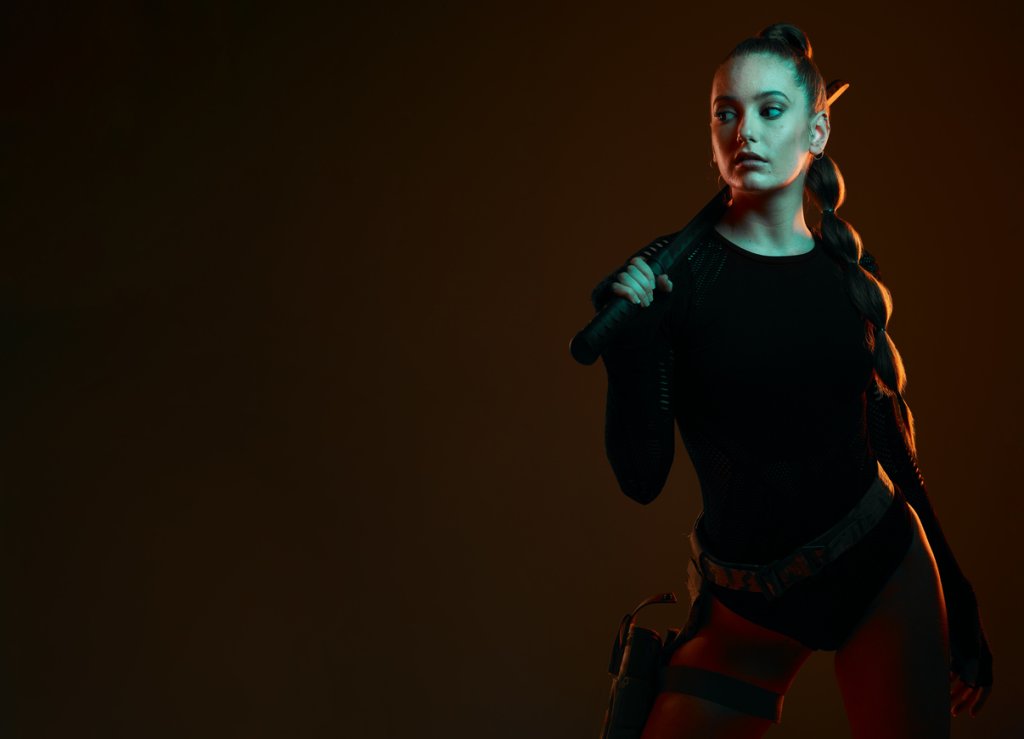 Warrior, woman and sword with space in studio for action, fight and safety from danger. Strong female vigilante, assassin or agent in scifi cosplay costume with weapon for mockup dark background