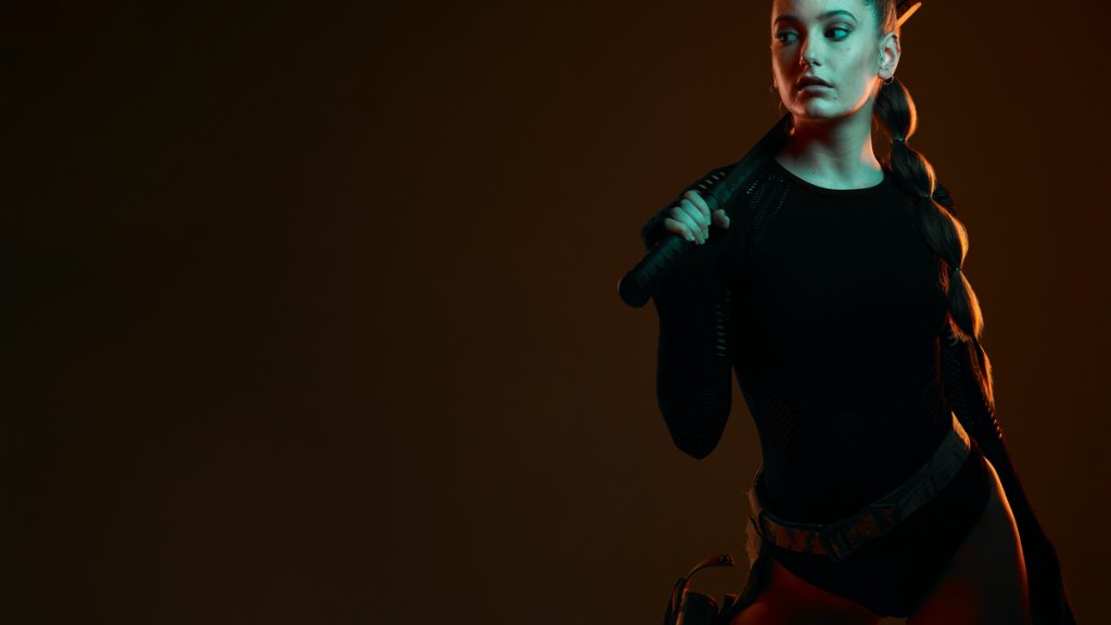 Warrior, woman and sword with space in studio for action, fight and safety from danger. Strong female vigilante, assassin or agent in scifi cosplay costume with weapon for mockup dark background