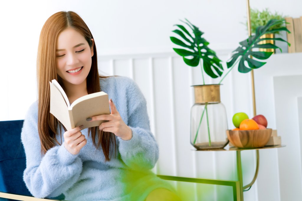 beauty asian female white dress long hair read book on blue modern armchair with clam and cheerful white bedroom interior background