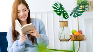 beauty asian female white dress long hair read book on blue modern armchair with clam and cheerful white bedroom interior background