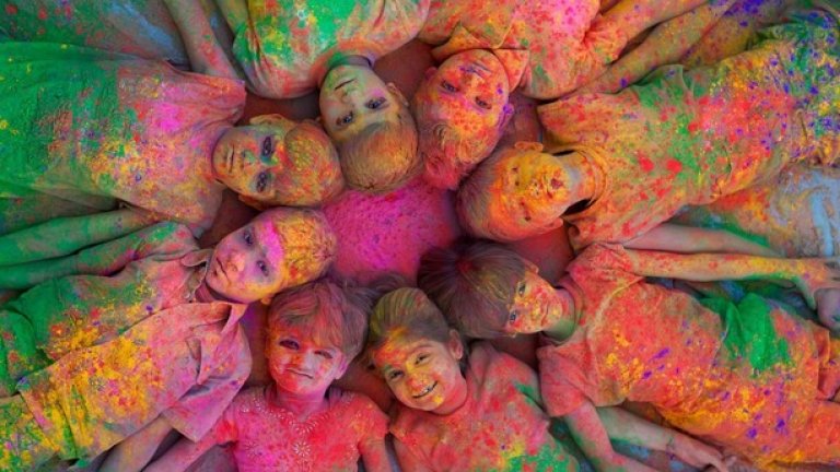 Разпръскването на цветен прашец във въздуха по време на фестивала Холи в Индия  символизира разпространението на радостта по света