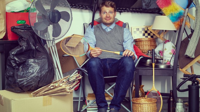 compulsive hoarding disorder concept - man hoarder with stuff piles sitting in the room