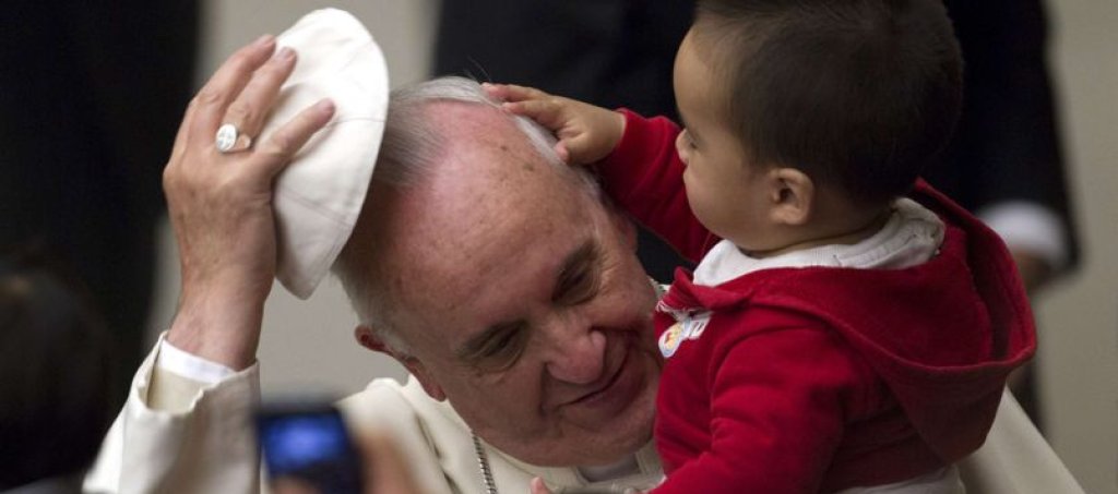 Pope Francis has his skull cap removed by a child during an audience with children in the Vatican