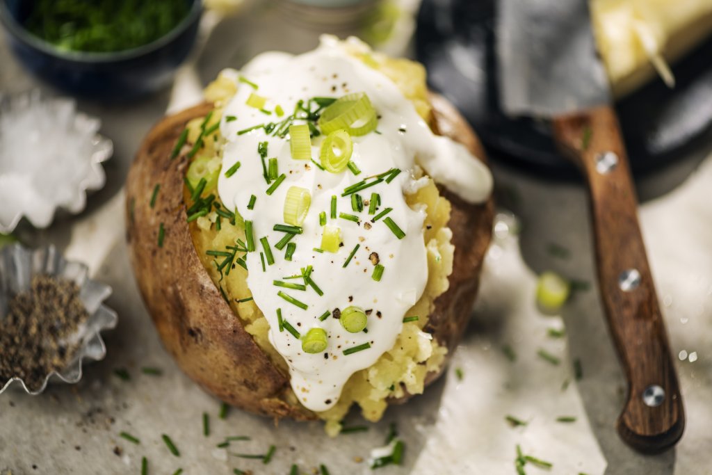 Пълнен картоф с фета и сметанаТова е една малко по-лека и свежа рецепта за пълнени картофи. За всяка порция ни трябва по един голям картоф – изпечен, разрязан и с намачкана леко вътрешност. За пълнежа смесваме 50 грама фета (или друго прясно сирене) и 50 грама заквасена сметана, подправяме със сол, пипер и зелени подправки по избор – магданоз, риган, зелен лук. Разбъркваме добре, пълним картофа и го поднасяме веднага.