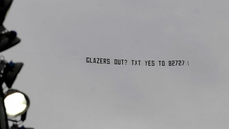 Май 2010: “Glazers Out? Txt Yes To 82727”
Май 2010-а. Феновете на Манчестър Юнайтед са настръхнали срещу американските собственици от фамилия Глейзър. Кампанията "Love United Hate Glazer" е в кулминацията си. 7 години по-късно Малкълм Глейзър е вече покойник, но клубът се управлява от наследниците му.
