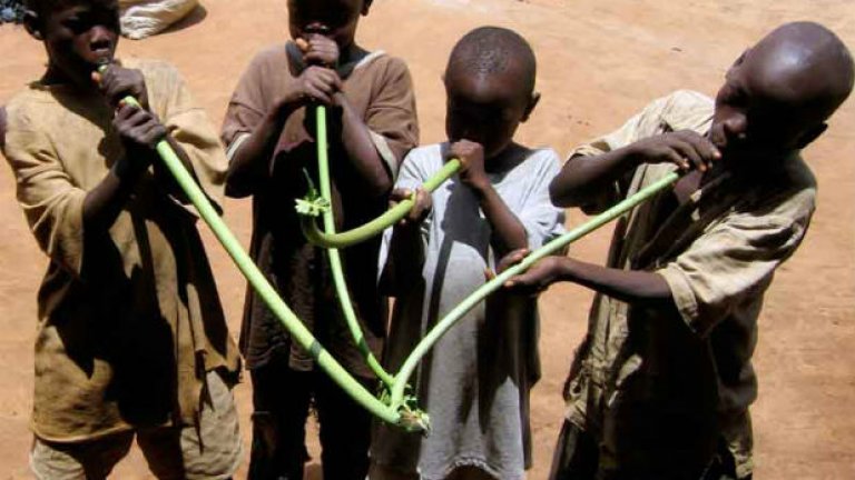 Деца в Уганда изучават стъбла от папая, които после се превръщат в музикални инструменти
