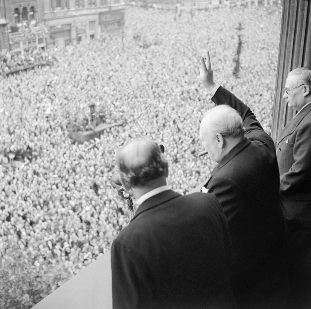 Winston_Churchill_waves_to_crowds_in_Whitehall_in_London_as_they_celebrate_VE_Day,_8_May_1945._H41849