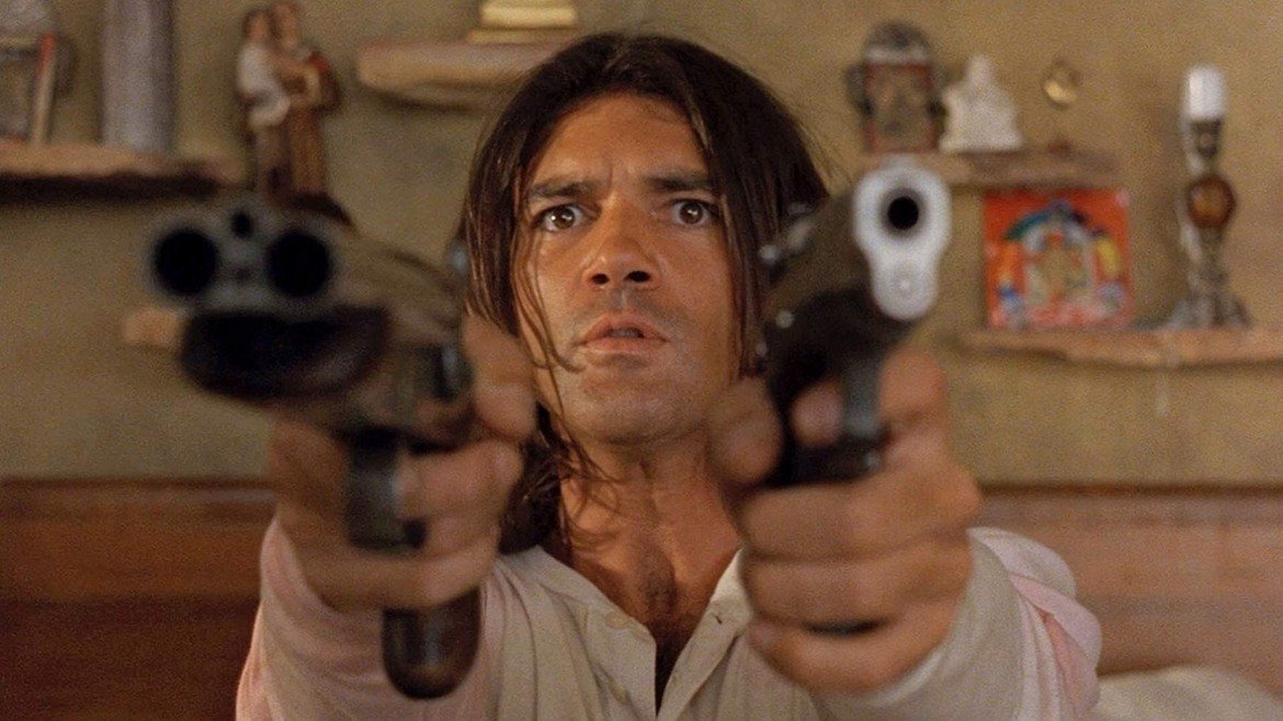 Desperado (Десперадо, 1995 г.)

Преди Джон Уик имаше друг кльощав екшън-герой - Ел Мариачи. "Десперадо" е нео-уестърн, който вдига на едно по-високо ниво концепциите, залегнали в дебютния филм на Родригес. 

В центъра на историята е Ел Мариачи (Антонио Бандерас) - мълчалив мъж, тръгнал да отмъщава на наркобарон за смъртта на любимата си. Отмъщението е кърваво и умело показано чрез визуалните таланти на Родригес. Всичко това за сметка на не толкова задълбочени персонажи и история, но фокусът все пак е върху развлекателния елемент - Бандерас едновременно като боец и любовник, Хайек като красива книжарка, и екшън под звуците на музиката на Los Lobos.