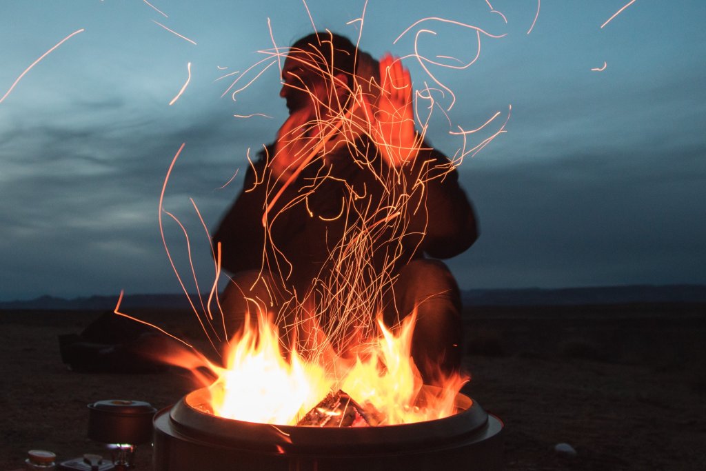 man-sitting-facing-fire-in-pot-during-night-2422968