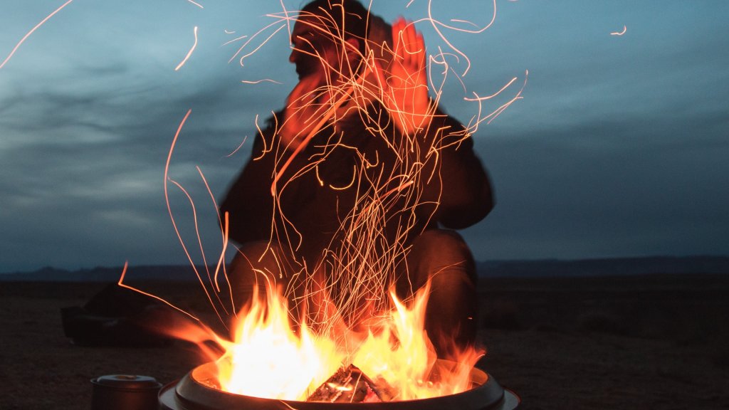 man-sitting-facing-fire-in-pot-during-night-2422968