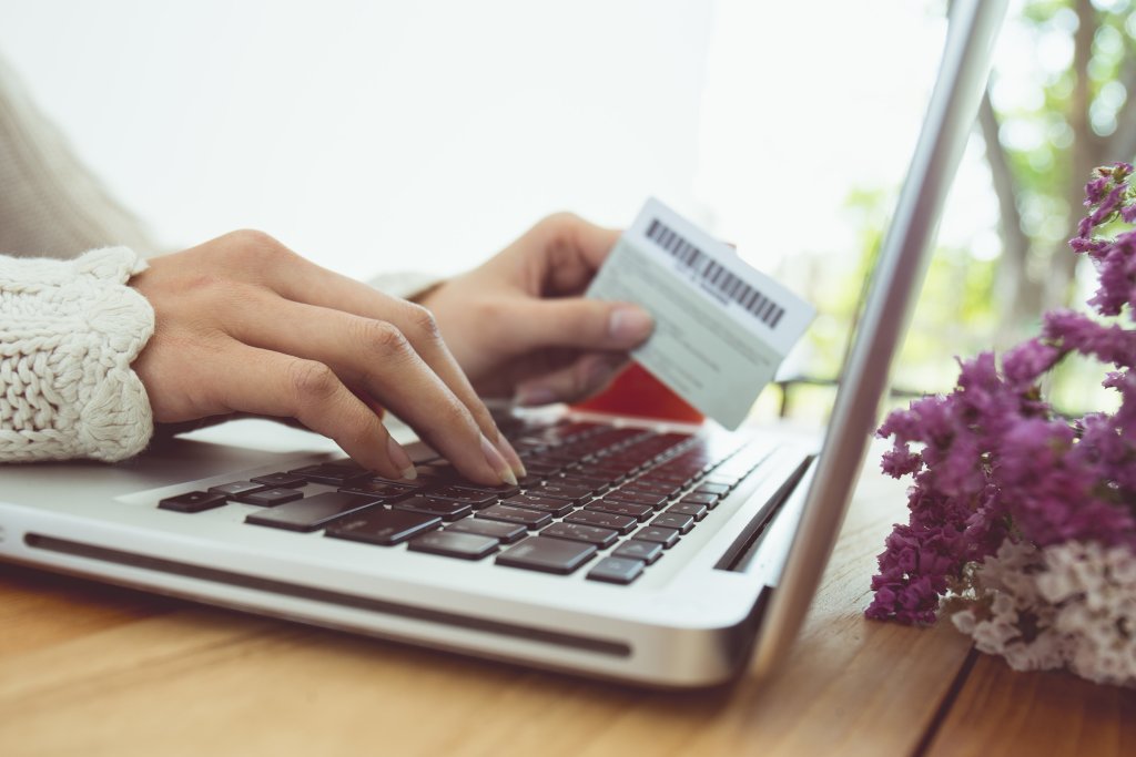Cropped Hands Of Woman Making Card Payment While Using Laptop At Table