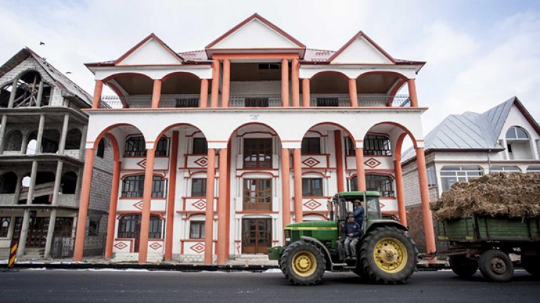 Трактор минава пред един от огромните палати на първа линия на главната улица на градчето