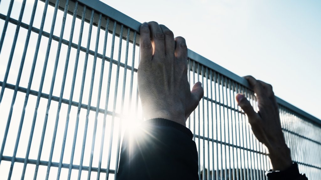 man climbing up a metal fence