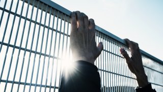 man climbing up a metal fence
