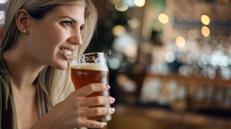 Close up of smiling woman enjoying in beer and looking away