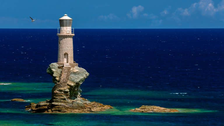 Турлитис, Гърция
Изглежда като генериран от ИИ, но не е – този фар на пристанището в Хора, на остров Андрос в Гърция, наистина е кацнал върху малката скала.
Намира се на около 200 метра в Егейско море, а в скалата са издълбани стълби, които водят до него. Фарът е първият автоматизиран в Гърция.
