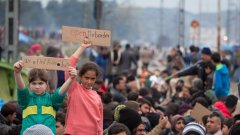Деца от бежанския лагер в Идомени до Македония държат табели с надписи "Избягахме от смъртта" и "Отворете границите"
