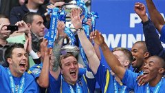 Капитанът на Уимбълдън Дани Кедуел държи здраво купата на победителите във финалния плейоф за влизане в Лига 2