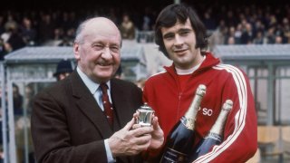 Бившият президент на Арсенал Денис Хил-Ууд (вляво) и Питър Стори (вдясно), който позира с наградата за играч на месеца и две бутилки шампанско през март 1971 г.
