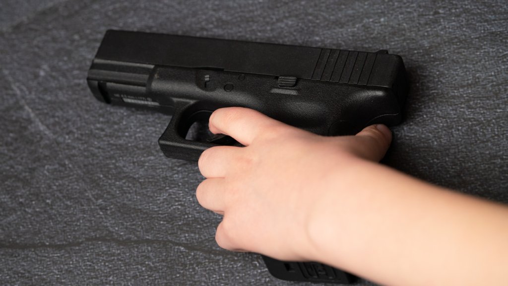 Young Caucasian White Child Kid Boy Hand Holding Black Gun Firearm Weapon