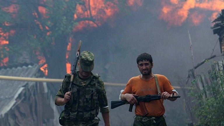 Южноосетински доброволци патрулират около горящото си село по време на войнaта между Русия и Грузия през 2008 г.