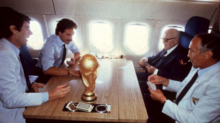 Купата се прибира у дома.
Италианският национален отбор се прибира от световното в Испания през 1982-ра, а на масата на треньора Енцо Беардзот (вдясно) и капитана Дино Дзоф (вляво) се играят карти и настроението е добро. Има и една малка позлатена подробност на масата...