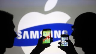 Men pose with Samsung Galaxy S3 and iPhone 4 smartphones in photo illustration in Zenica