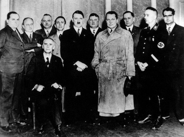 Още един мъж е излишен: Фюрерът позира със своите довереници. Годината е 1934, а Хитлер няма съмнение в лоялността на човека, който се намира по средата - между него и Гьоринг. Той стои зад шефа на щурмоваците Ернс Рьом и неговите специални части…