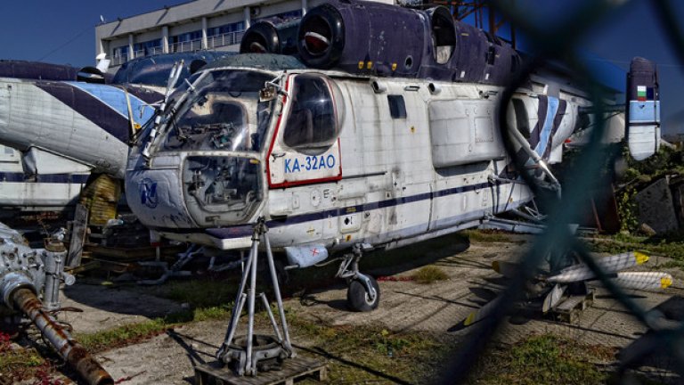 Бракувани вертолети Ка-32 АО на стоянка край летище София. Ка-32 са многоцелеви хеликоптери, предназначени за превоз на хора и товари. Използват се в широк кръг дейности, между които спасителни операции и строително-монтажни работи. Характерно за тях е, че използват съосна схема за париране на реактивния момент, включваща два носещи винта, разположени един над друг и въртящи се в противоположни посоки. Машините тук са собственост на частна българска фирма, но поради изтекъл ресурс са използвани за резервни части.