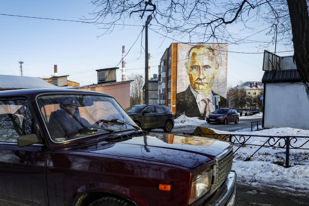Мъж преминава с автомобила си Лада Рива 2107 покрай голям стенопис, изобразяващ руския президент Владимир Путин, върху пететажна жилищна сграда в Кашира, Московска област, Русия.
Дата: 12 януари 2023 г.
