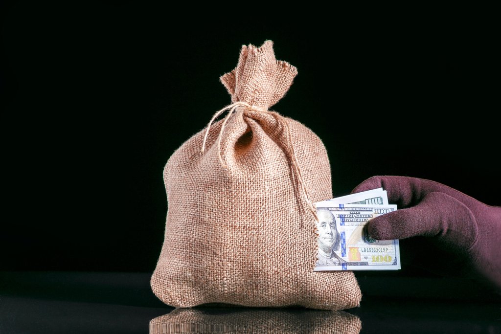 Stealing Money. Money loss, tear in bag, money sack with hole and hand grabbing a pile of dollar banknotes