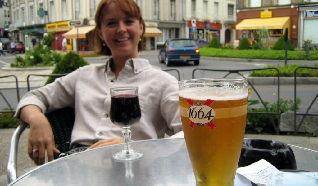 Lady_relaxing_next_to_glass_of_red_wine_and_glass_of_1664_beer