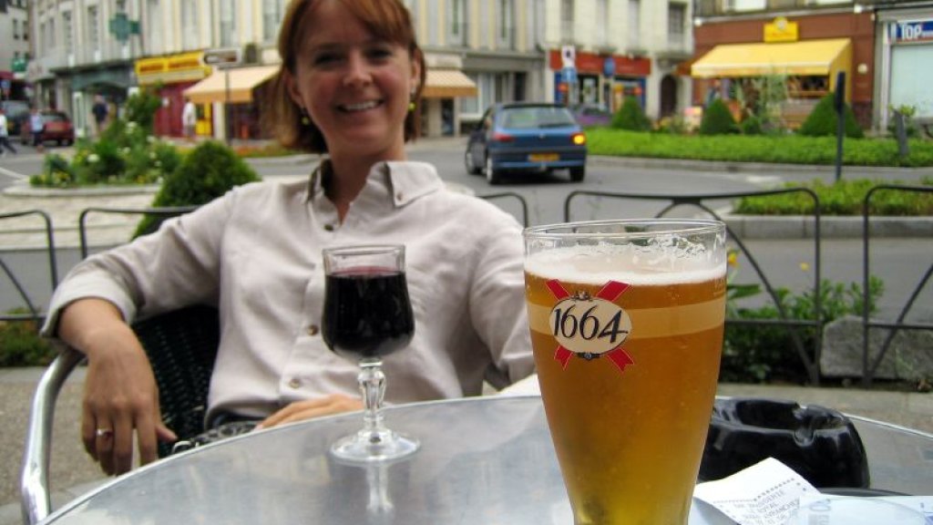 Lady_relaxing_next_to_glass_of_red_wine_and_glass_of_1664_beer