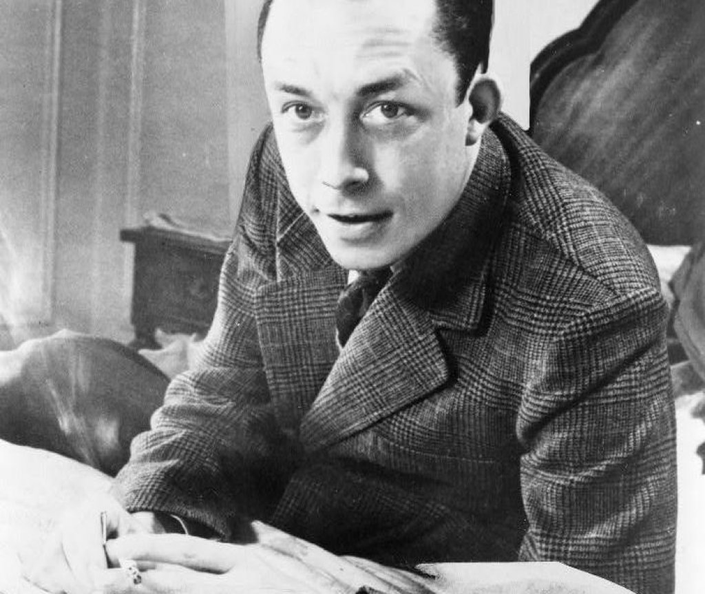 Albert_Camus,_gagnant_de_prix_Nobel,_portrait_en_buste,_posé_au_bureau,_faisant_face_à_gauche,_cigarette_de_tabagisme