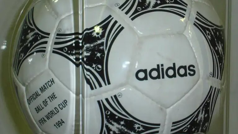 Questra (1994)
За първото световно първенство, проведено в Съединените щати, Adidas представя Questra. Тя е най-футуристичният, високопроизводителен модел, използван на мондиал. Основната иновация е слой от полистиролова пяна от външната страна на топката, за която се казва, което прави кълбото по-меко на допир и по-лесно за контрол, като същевременно се увеличава скоростта му при удар. Ефектът е очевиден. Нито един отбор не запази "суха" мрежа на 1/4-финалите, а на 1/8-финалите успяха три от 16. По ирония на съдбата финалът беше едно от само трите равенства 0:0 в целия турнир, който ще носим в сърцата си завинаги. Върхът САЩ'94 на българския футбол едва ли ще бъде повторен.