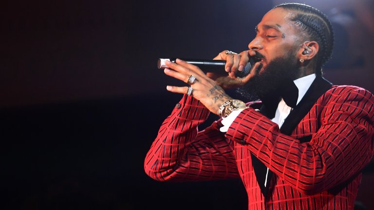 Nipsey Hussle
Роденият в семейство на бежанци от гражданската война в Еритрея Hussle израства като член на улични банди в Лос Анджелис. Пробива на музикалната сцена след 2010 г. и си партнира с имена като Drake и Snoop Dogg, а пък през 2018 и 2019 г. получава номинации за “Грами”.
Никога обаче не успява да се откъсне от миналото си. Hussle е застрелян от негов приятел, с когото заедно са членували в банда като младежи, след като рапърът го нарича “доносник”. През 2020 г. Nipsey Hussle получава посмъртно две награди “Грами”.