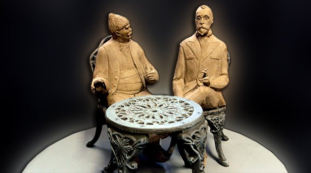 Бай Ганьо и създателят му Алеко Константинов разговарят на маса, писателят ще държи пура, а героят му - круша.