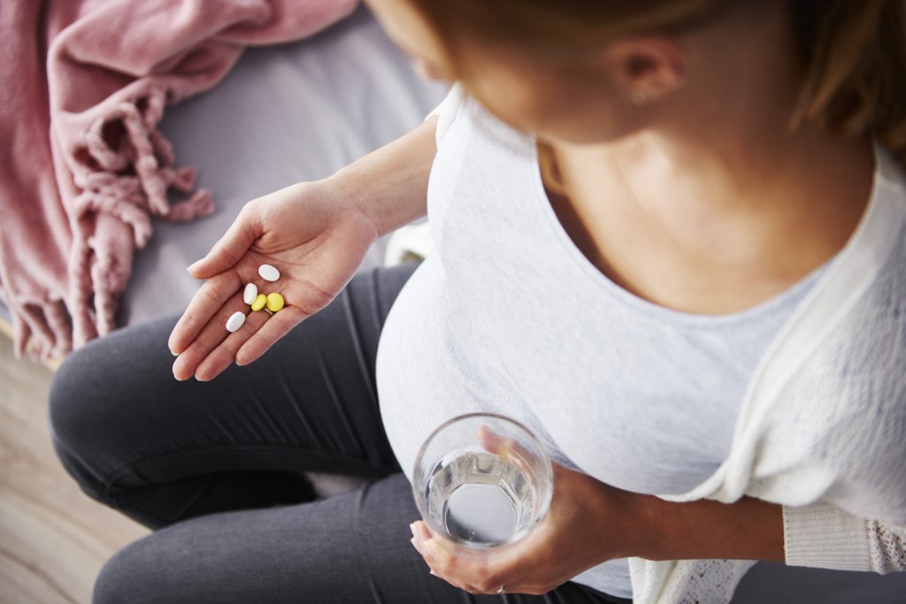Young pregnant woman taking medicine